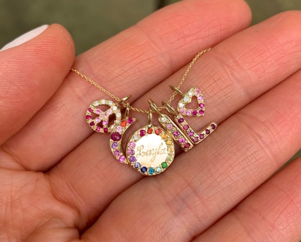 Mini Charm Jewels - Size guide for size of the charms - holding gold peace charm, gold moon charm, gold circle charm, gold skinny bar charm, gold letter charm and heart charms with personalized gemstones