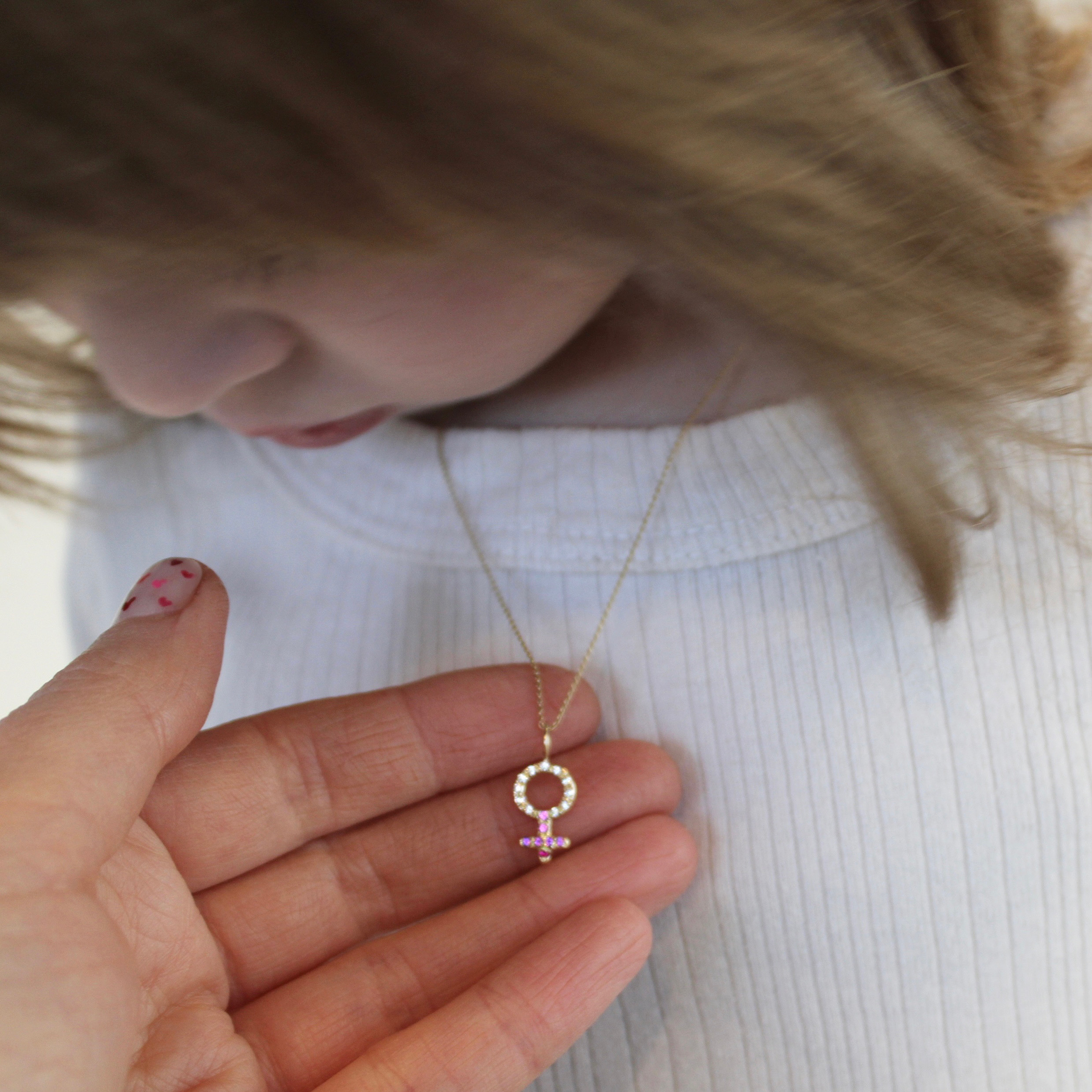 international-womens-day holding up the female symbol charm necklace on daughter