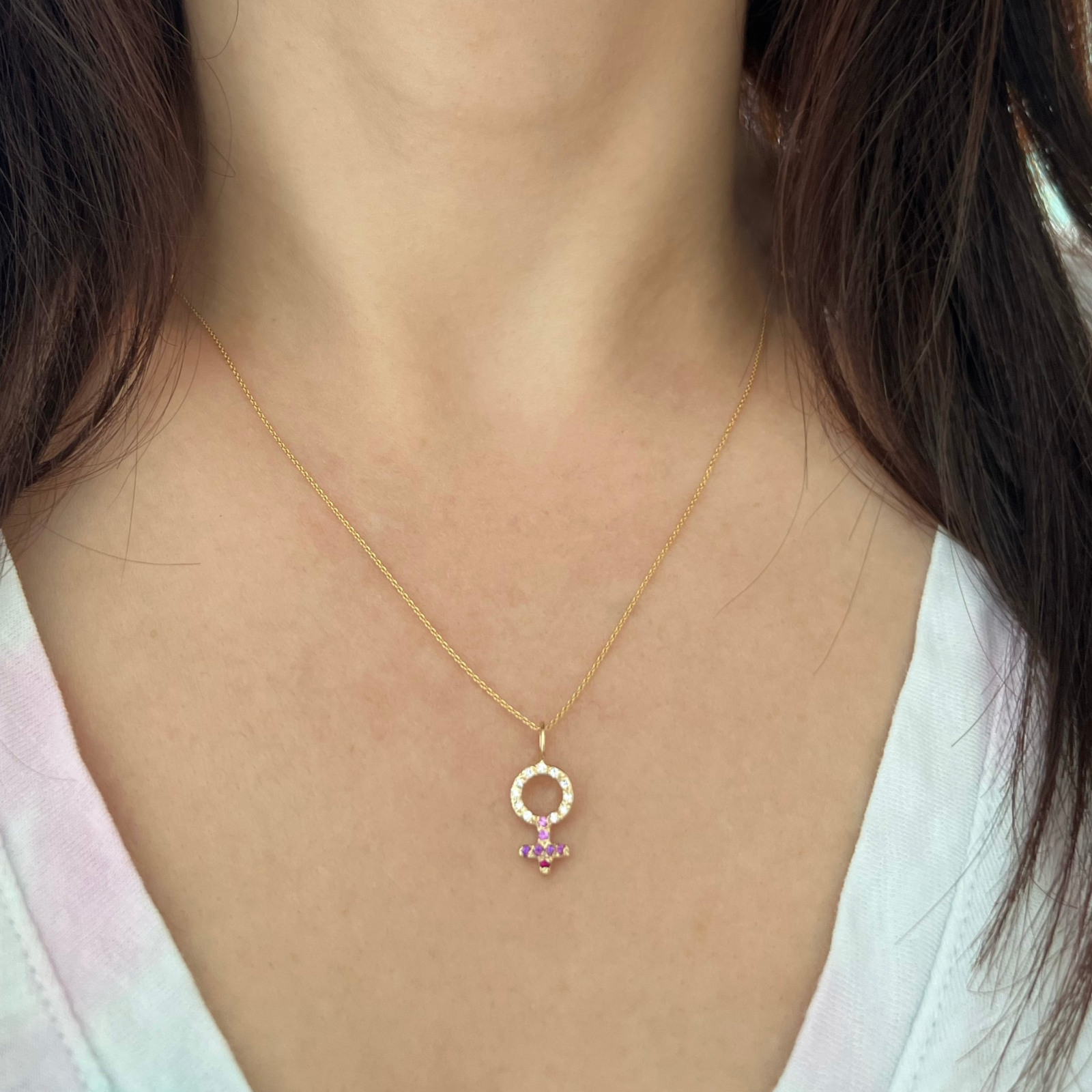 wearing the custom female charm necklace in 14k yellow gold with white dimaonds and pink gemstones