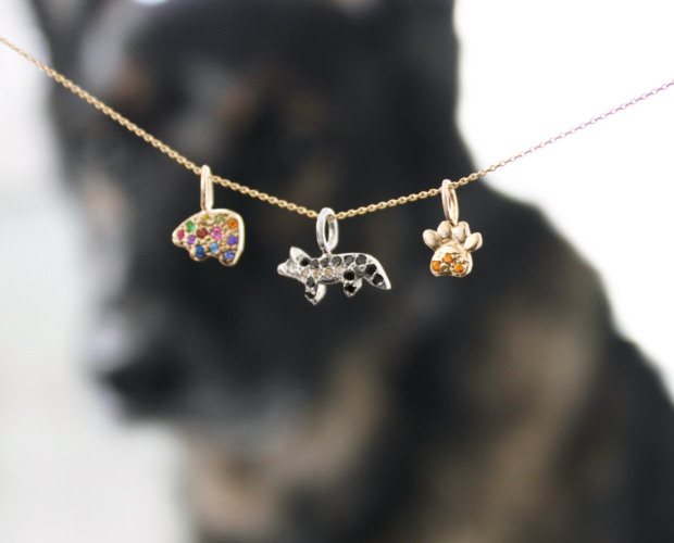 bear charm with multicolor gemstones, german shepherd charm with black and champagne diamonds, and the paw charm with citrine gemstones in the foreground with "bear" the german shepherd in the background
