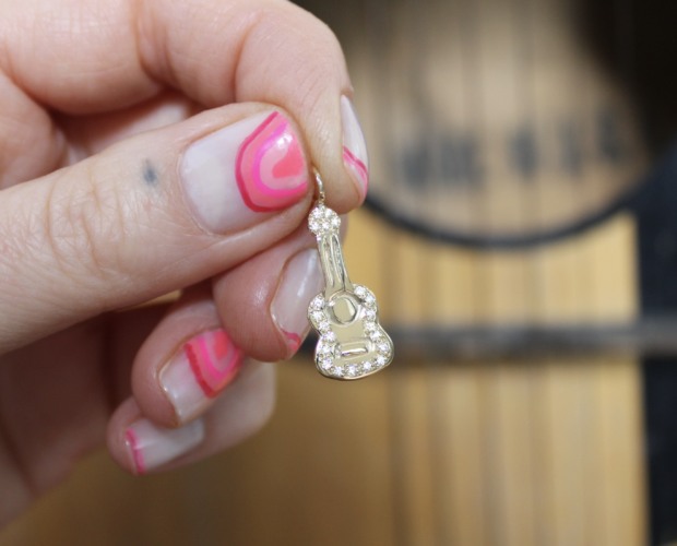 close up holding the gold diamond guitar charm