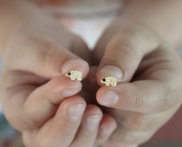 holding the tiny gold polar bear diamond stud earrings