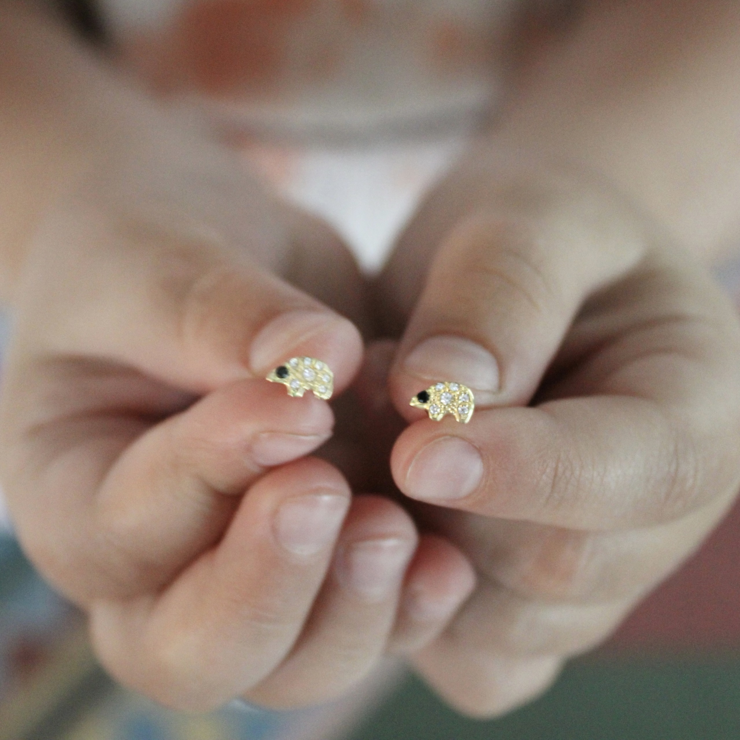 holding-the-gold-diamond-polar-bear-studs-earrings holding the tiny gold polar bear diamond stud earrings
