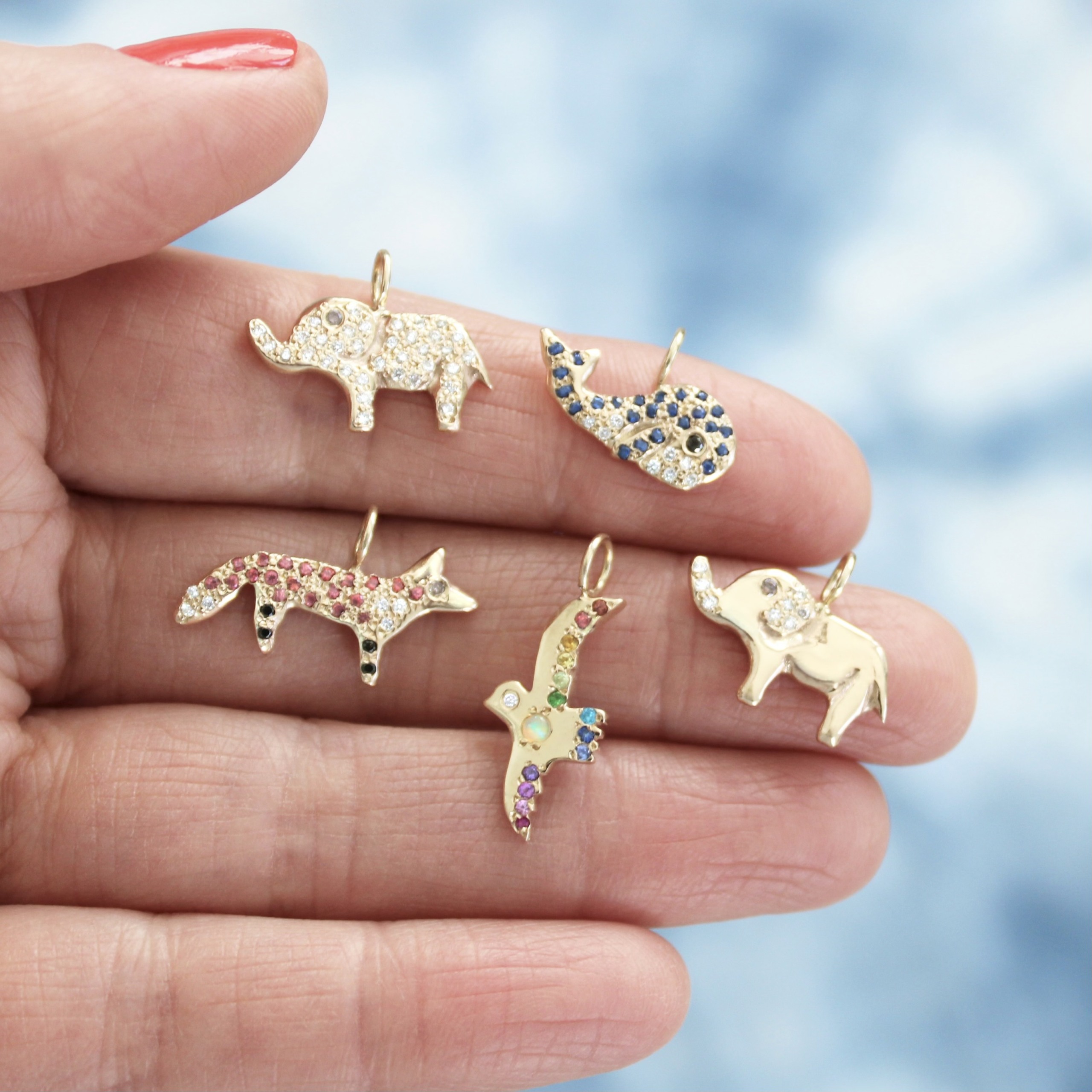 close-up-holding-animal-charms-gold-diamonds-gemstones